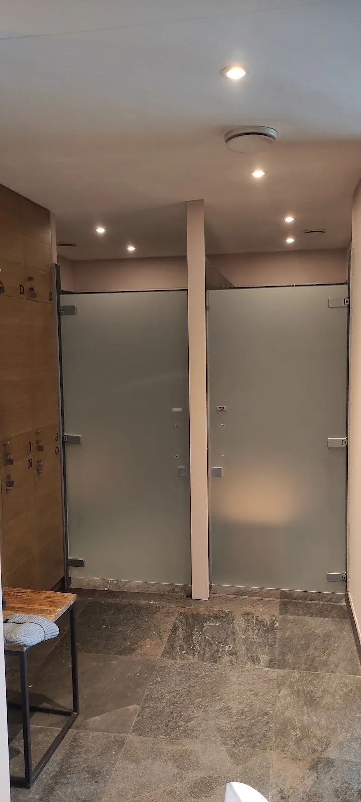 Cabines de douche du spa Yves Rocher à La Gacilly traitées au Mat Blanc PVC pour milieu humide, avec découpes au millimètre autour des charnières et des poignées