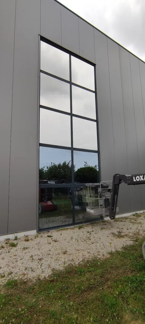 Façade vitrée de l'atelier Artipole à Plescop traitée au film solaire Silver 385 XC, pose réalisée à la nacelle