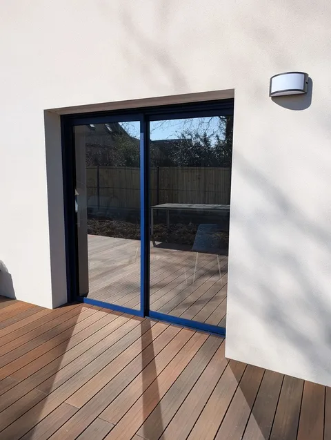 Baie coulissante d'une maison neuve à Locoal-Mendon traitée au film solaire effet miroir Chrome 270 XC